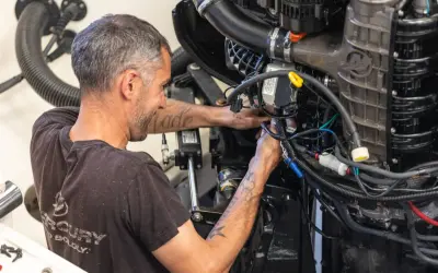 Un mécanicien s'affaire sur un moteur électrique, câbles et tuyaux visibles. Il sait comment tester un moteur électrique pour assurer son bon fonctionnement.