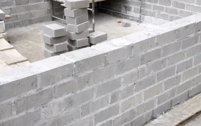 Budowa fundamentów z bloczków betonowych. Zastanawiasz się, ile kosztuje bloczek fundamentowy? Oto stosy gotowych do użycia elementów.