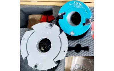 Deux fraises de toupie occasion, une grise "ISOCELE" et une bleue "ISO", prêtes pour des travaux de menuiserie.