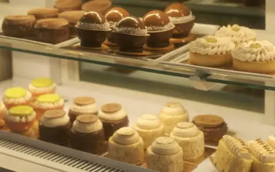 Słodkości w kawiarni cukierni Cafe Marona Gruszecki: czekoladowe kule, tartaletki z kremem i kolorowe babeczki.