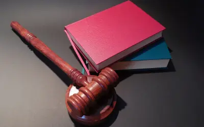 Drewniany młotek sędziowski i stos książek. Jak oddać książki do biblioteki? Zwróć je, zanim zostaną wycofane z obiegu.