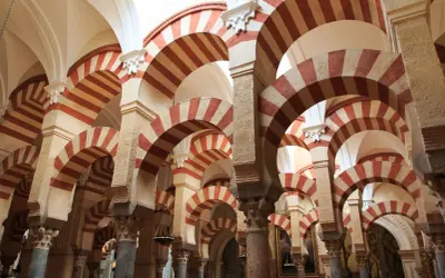 Las icónicas partes de la mezquita de Córdoba: arcos de herradura bicolores y columnas que crean un laberinto arquitectónico.