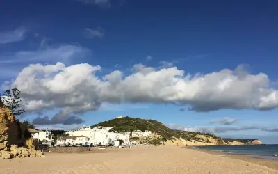 Sonne, Sand und weiße Häuser: Ein malerischer Blick auf Salema, Portugal, mit dem Atlantik und dramatischen Wolken.