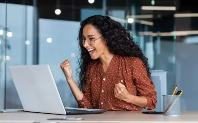Excited woman celebrates fast Google Drive upload speed on her laptop.