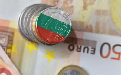 Monety z flagą Bułgarii na tle eurobanknotów. Waluta Bułgaria w kontekście europejskim.