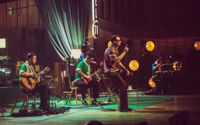 Zespół Mrozu na scenie MTV Unplugged. Wokalista śpiewa, gitarzyści grają, a perkusista wybija rytm.