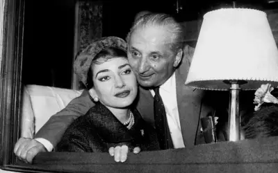 Maria Callas i Giovanni Battista Meneghini, uśmiechnięci, w bliskim uścisku.
