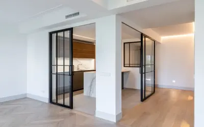 Puertas correderas de cristal negro separan la cocina moderna. Se planea poner baldas entre dos paredes para maximizar el espacio.