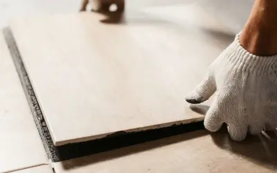 A gloved hand places a tile. Walking on tile too soon can cause shifting and unevenness.