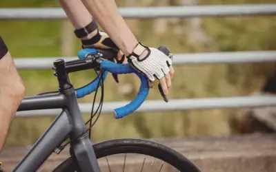 Rowerzysta w rękawiczkach trzyma kierownicę. Czas przekroczyć prog mleczanowy i przyspieszyć.