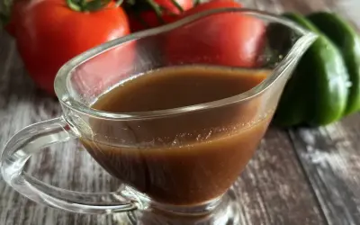Sos balsamiczny w sosjerce, na tle pomidorów i zielonej papryki. Idealny do sałatek i mięs.