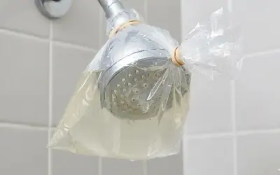 Doccia con soffione avvolto in un sacchetto pieno di liquido, per rimuovere residui di autoabbronzante che si toglie con l'acqua.