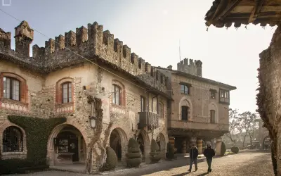 Passeggiata nel borgo di Grazzano Visconti, tra antichi palazzi in pietra e mattoni, con torrette merlate e archi.