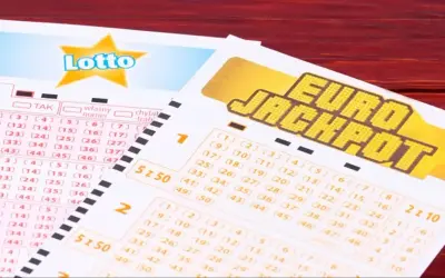 Kupony Lotto i Eurojackpot, do której wysyłamy eurojackpot, leżą na drewnianym stole.