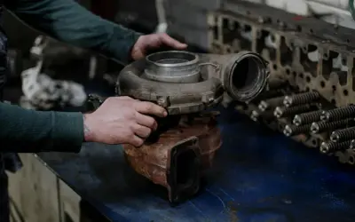Mechanik trzyma turbosprężarkę, przygotowując się do wymiany zaworu N75.
