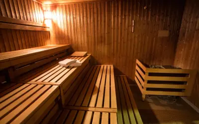 Drewniane ławy i kamienny piec w przytulnej czeskiej saunie. Czeska sauna co to? To relaks i gorąco!