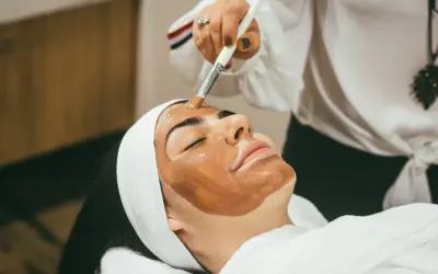 Kobieta z maską na twarzy, przygotowująca się do zabiegu hydrodermabrazji.