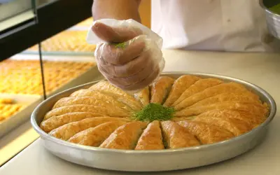 Słodka baklava, co to za przysmak? Warstwy ciasta filo, orzechy i syrop. Posypka z pistacji dodaje uroku.