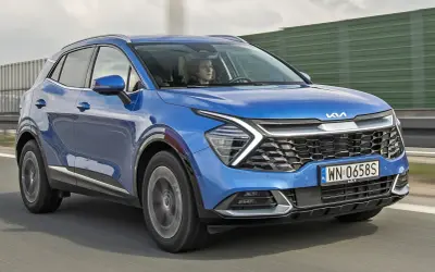 Nowa Kia Sportage w kolorze niebieskim jedzie po drodze.