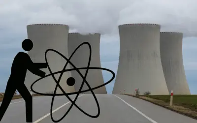Człowiek z atomem przed chłodniami kominowymi elektrowni jądrowej symbolizuje potencjalne wady elektrowni jądrowej.