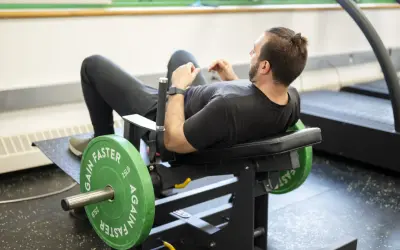 Man tränar höfterna på en hip thrust maskin med viktskivor.