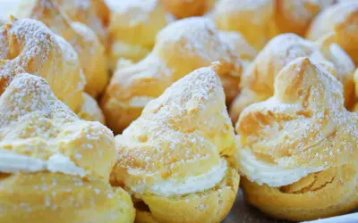 Une assiette de choux à la crème, saupoudrés de sucre glace. Ces petites merveilles de chou patisserie sont prêtes à être dégustées.