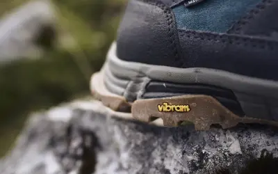 Nahaufnahme eines Wanderschuhs mit Vibram-Sohle auf einem Stein. Mögliche vibram sohle nachteile wie Abnutzung sind hier nicht sichtbar.
