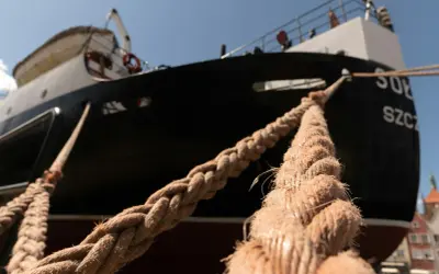 Gros cordage tressé, essentiel au point d'amarrage d'un navire noir et blanc sous un ciel bleu.