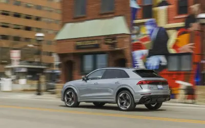 Srebrny Audi RS Q8 pędzi ulicą obok kolorowego muralu. Sprawdź aktualną audi rsq8 cena i możliwości tego SUV-a.