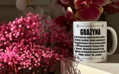 Kubek z napisem "Grażyna" na imieniny, otoczony delikatnymi, różowymi kwiatami.