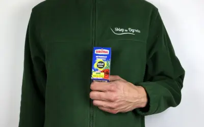 Dłoń trzyma opakowanie środka ochrony roślin Saprol.