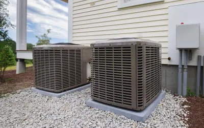 Dwa klimatyzatory przy nowoczesnym domu energooszczędnym, otoczone białym żwirem.