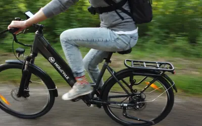 Osoba na rowerze elektrycznym Molicyle z amortyzacją pokonuje leśną ścieżkę.