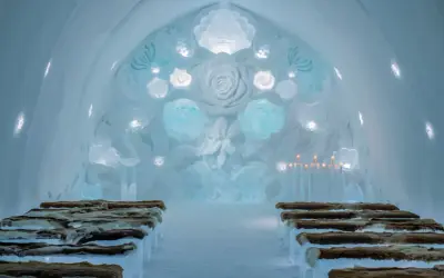 Vacker iskyrka i ett igloo hotell Sverige. Bänkar av is med renskinn, isrosor och levande ljus skapar en magisk atmosfär.