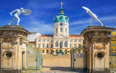 Pałac Charlottenburg w Berlinie, z jego kopułą i bogatymi zdobieniami, zachwyca w stylu na końcu baroku. Dwie białe rzeźby wojowników strzegą wejścia.