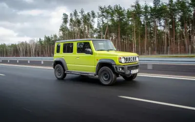 Jaskrawozielony suzuki jimny 5-drzwiowy na drodze. Sprawdź suzuki jimny 5-drzwiowy cena i możliwości.