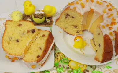 Pyszna babka drożdżowa z rodzynkami, ozdobiona lukrem i kandyzowaną skórką pomarańczową, w towarzystwie wielkanocnych kurczaczków.
