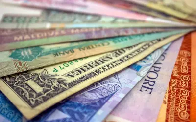 Różne waluty świata ułożone wachlarzowo, od dolara amerykańskiego po banknoty z Singapuru i Sri Lanki. Ile jest walut na świecie? Tyle, ile widzisz tutaj i jeszcze więcej!