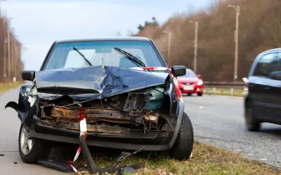 Un coche negro destrozado en la carretera, parece que fue un accidente grave. Un punto negro en la carretera que nadie quiere ver.