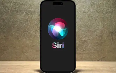 Na ekranie telefonu widnieje logo Siri, które wygląda jak kolorowa, świetlista kula.