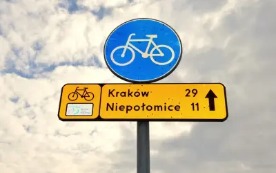 Znak drogowy informuje, że kiedy rowerzysta ma pierwszeństwo, kieruje się na Kraków (29 km) i Niepołomice (11 km).