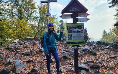 Kobieta na szczycie Łysicy, 614 m n.p.m., przy drogowskazie szlak łysica - kakonin. Jesień w pełni, liście na ziemi.