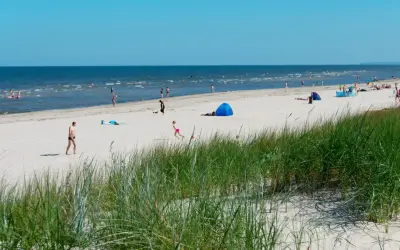 Menschen genießen einen sonnigen Tag am Strand der Ostsee. Nach der Fahrt mit dem Zug von Berlin ist dies eine willkommene Erfrischung.