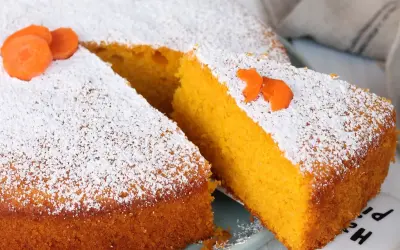 Una fetta di torta Camilla, soffice e arancione, cosparsa di zucchero a velo e decorata con carote.