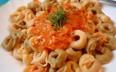 Kolorowe tortellini w kremowym sosie pomidorowym, udekorowane świeżą rukolą. Pyszny sos do tortellini kusi aromatem.