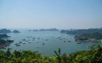 Widok na zatokę Ha Long z licznymi łodziami i statkami, otoczoną zielonymi, skalistymi wyspami.
