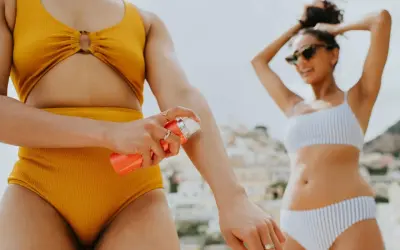 Frau trägt Sonnencreme auf, um sich vor der Sonne zu schützen. Welcher LSF ist wohl der richtige für diesen sonnigen Tag am Strand?
