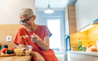 Femme souriante de 50 ans savoure une salade fraîche. Une alimentation saine pour maîtriser les calories.