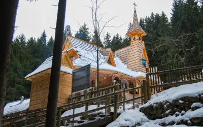 Drewniany kościółek, najwyżej położony kościół w Tatrach, otoczony ośnieżonym lasem.