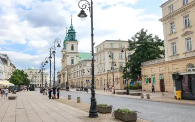 Spacer po Krakowskim Przedmieściu w Warszawie, z zabytkowymi kamienicami i kościołem w tle.